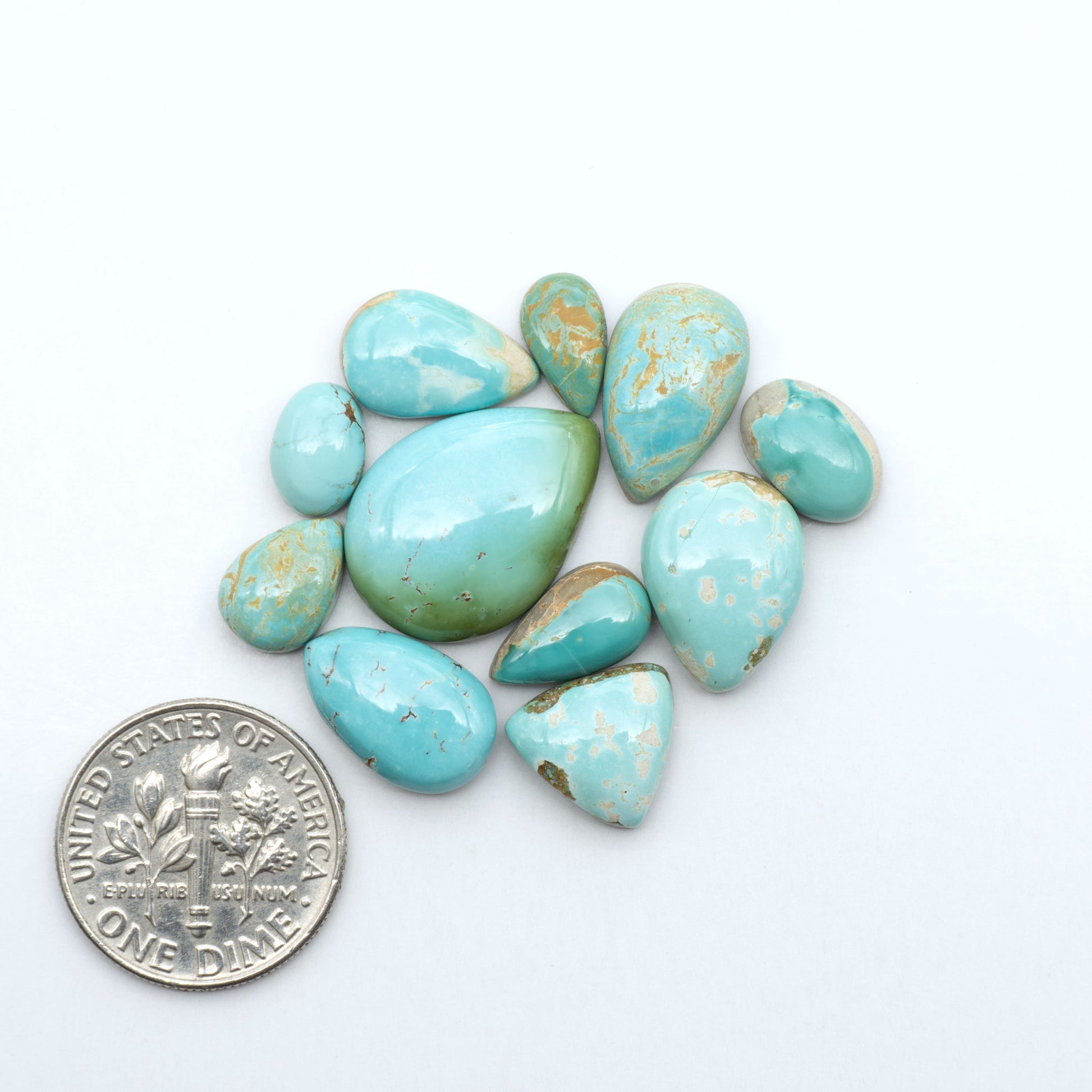 Royston Turquoise cabochons, blue-green color with natural matrix, polished stones on a white background, with a US dime for scale