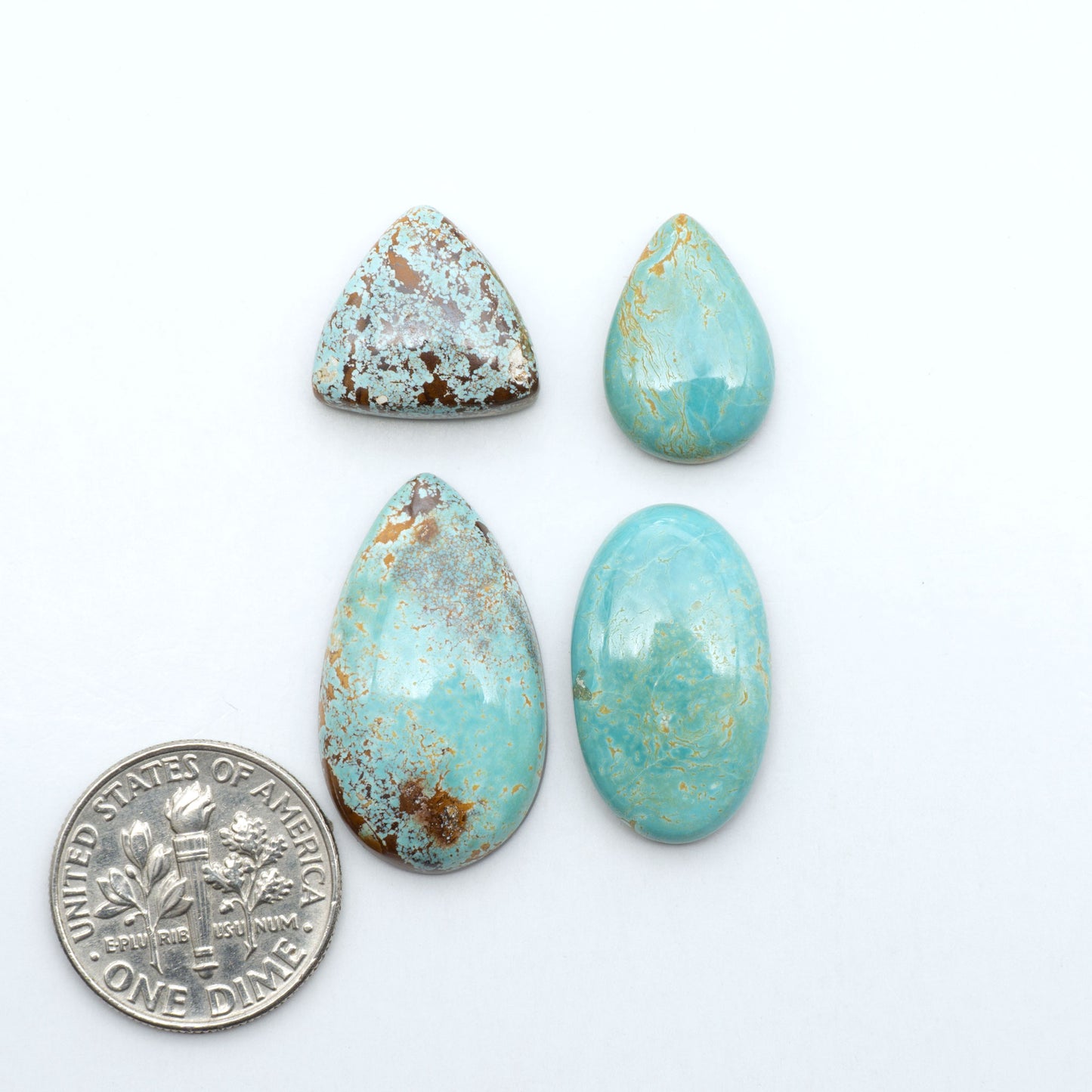 Royston Turquoise cabochons, blue-green color with natural matrix, polished stones on a white background, with a US dime for scale