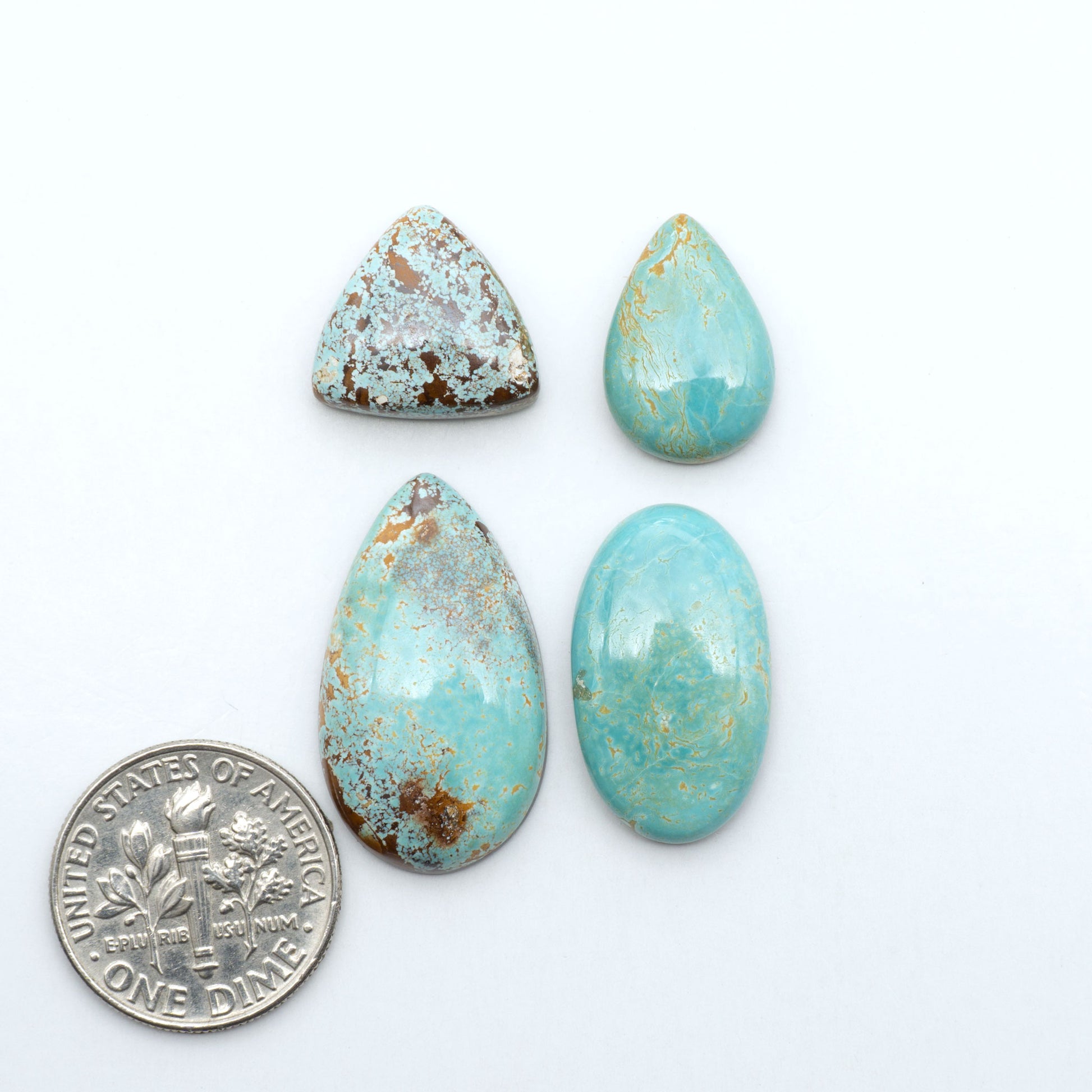Royston Turquoise cabochons, blue-green color with natural matrix, polished stones on a white background, with a US dime for scale