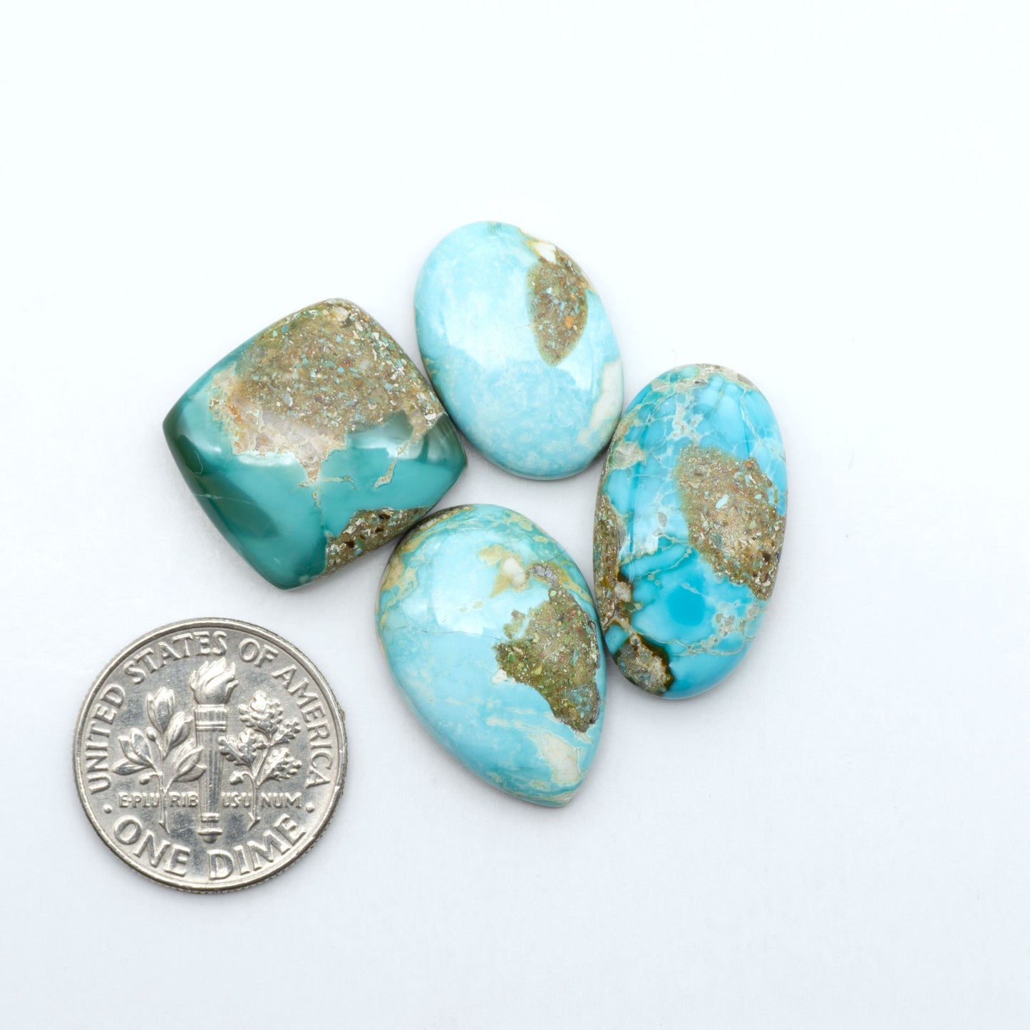 Royston Turquoise cabochons, blue-green color with natural matrix, polished stones on a white background, with a US dime for scale