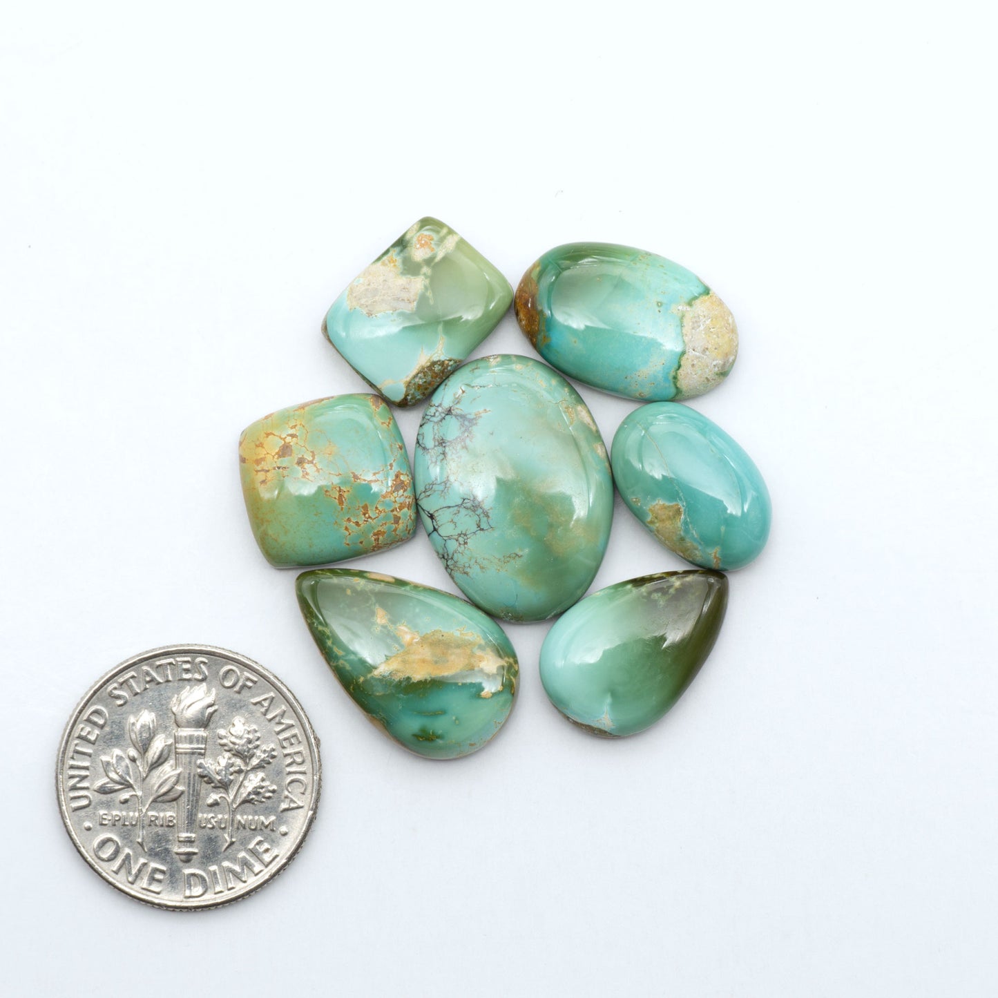 Royston Turquoise cabochons, blue-green color with natural matrix, polished stones on a white background, with a US dime for scale