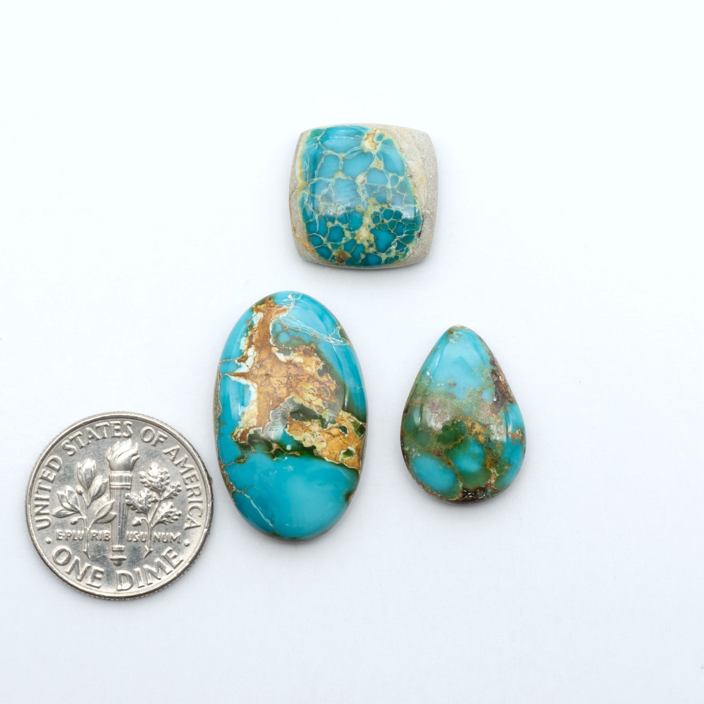 Royston Turquoise cabochons, blue-green color with natural matrix, polished stones on a white background, with a US dime for scale