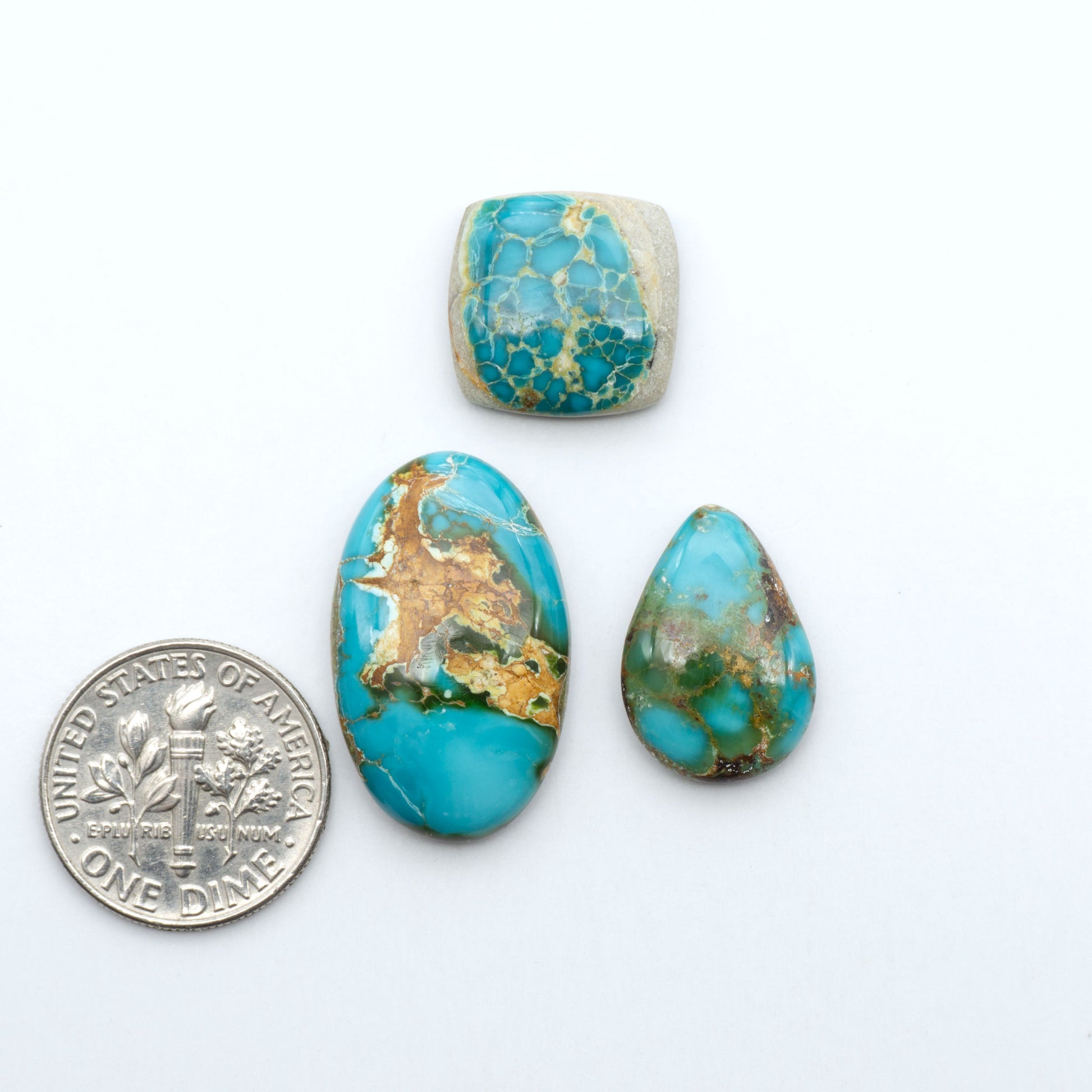Royston Turquoise cabochons, blue-green color with natural matrix, polished stones on a white background, with a US dime for scale