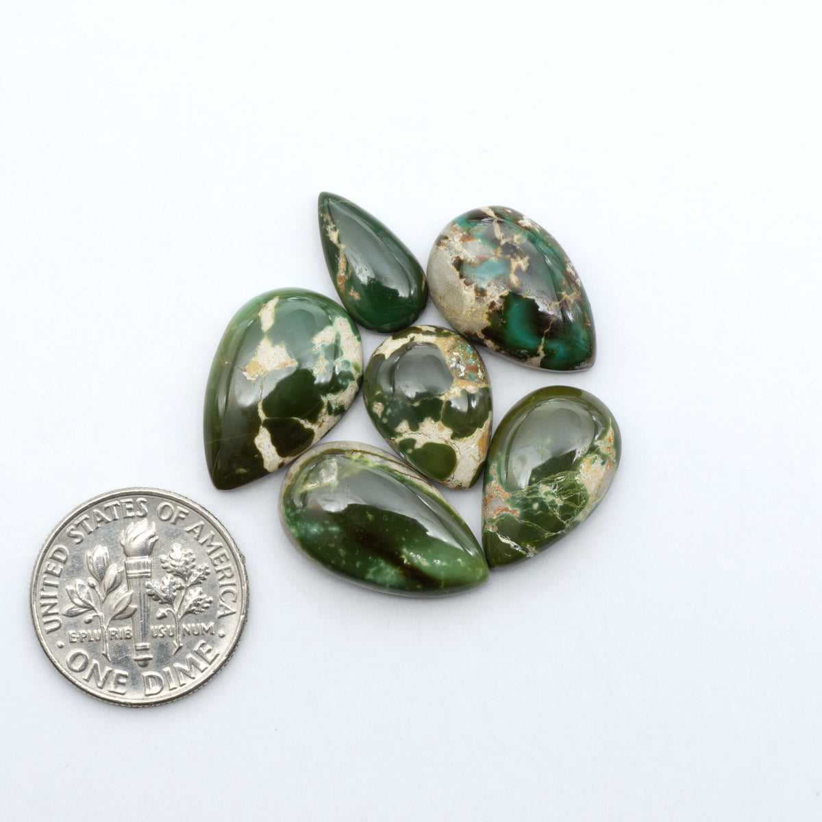 Royston Turquoise cabochons, blue-green color with natural matrix, polished stones on a white background, with a US dime for scale