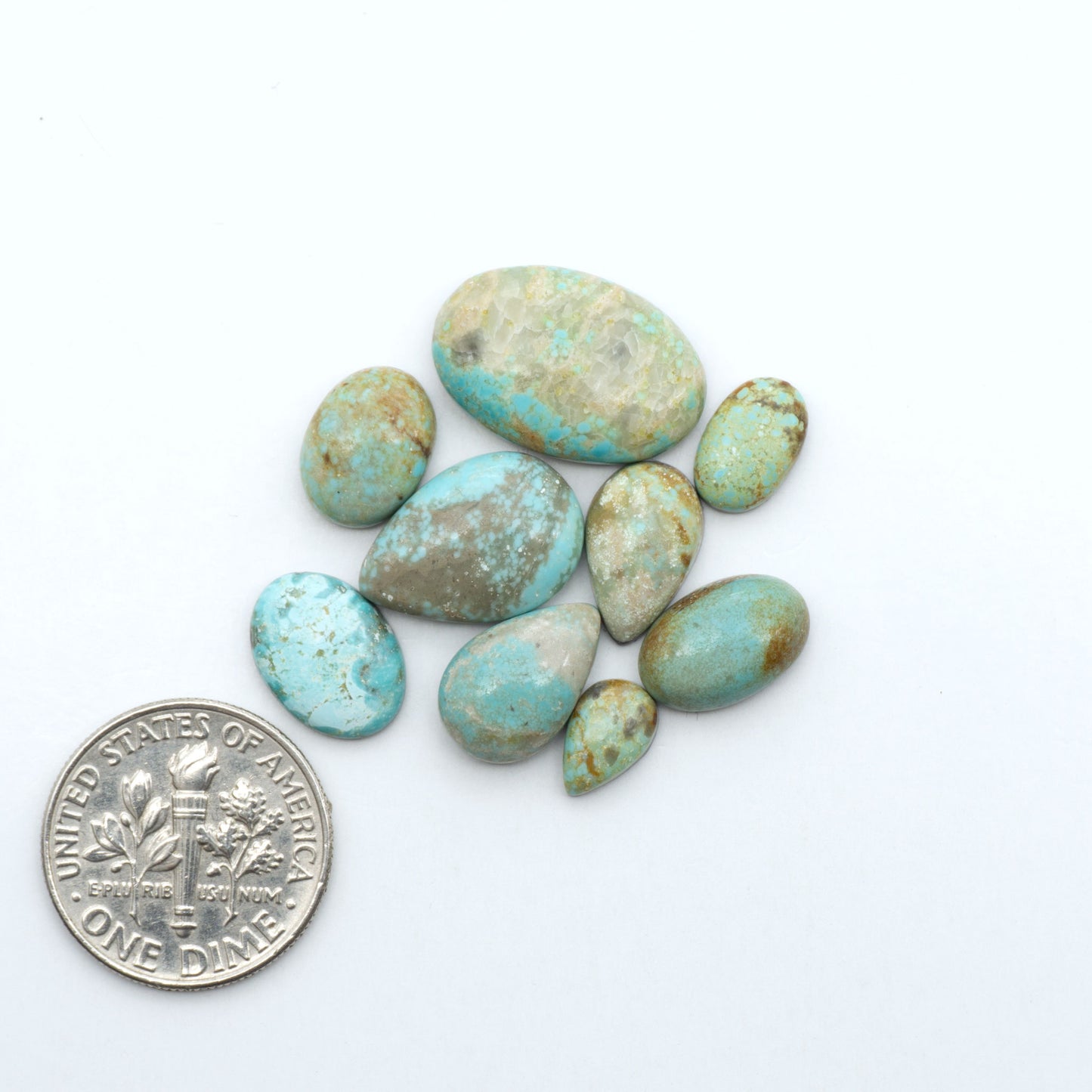 Number 8 Turquoise cabochons, blue and green color with brown matrix, polished stones on a white background, with a US dime for scale