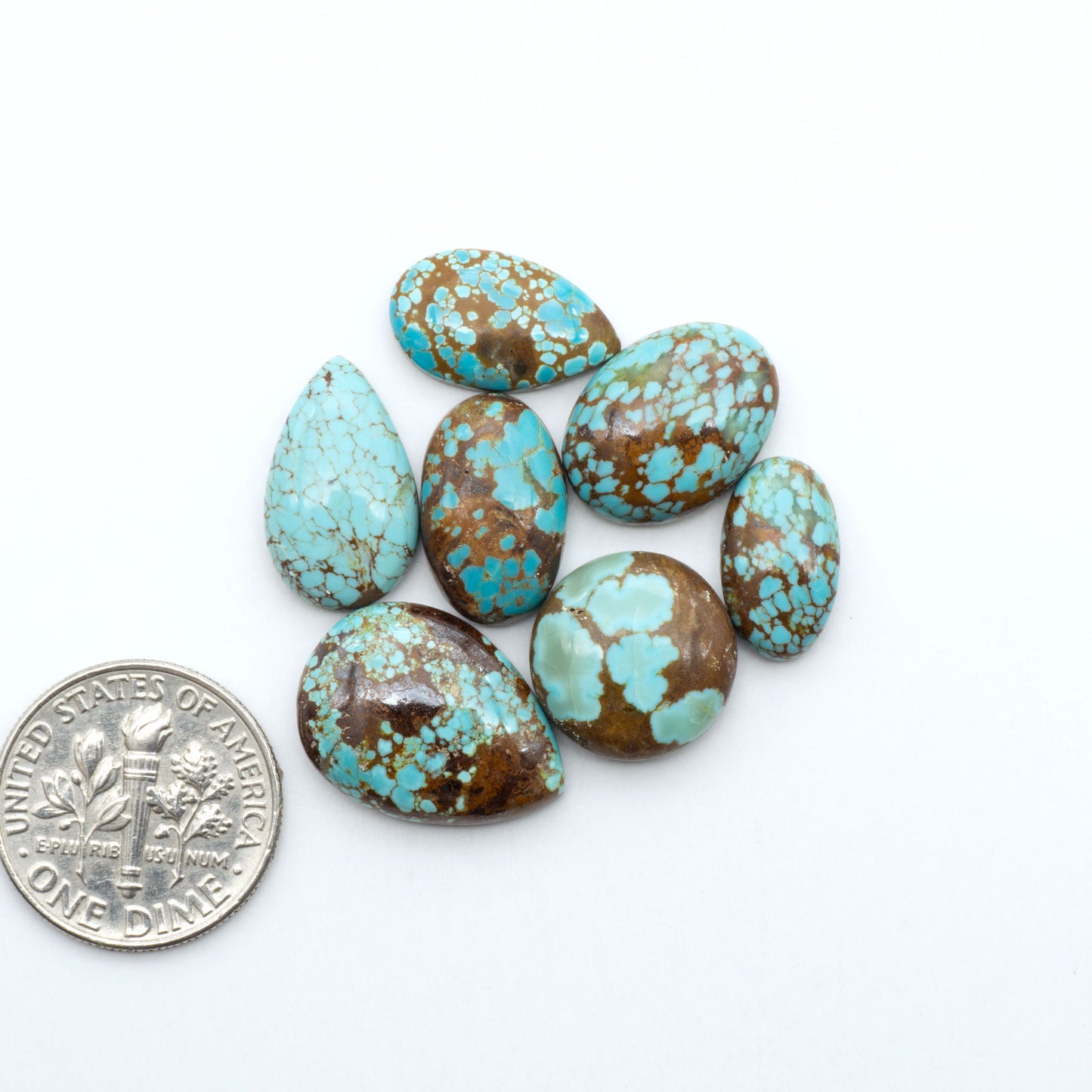 Number 8 Turquoise cabochons, blue and green color with brown matrix, polished stones on a white background, with a US dime for scale