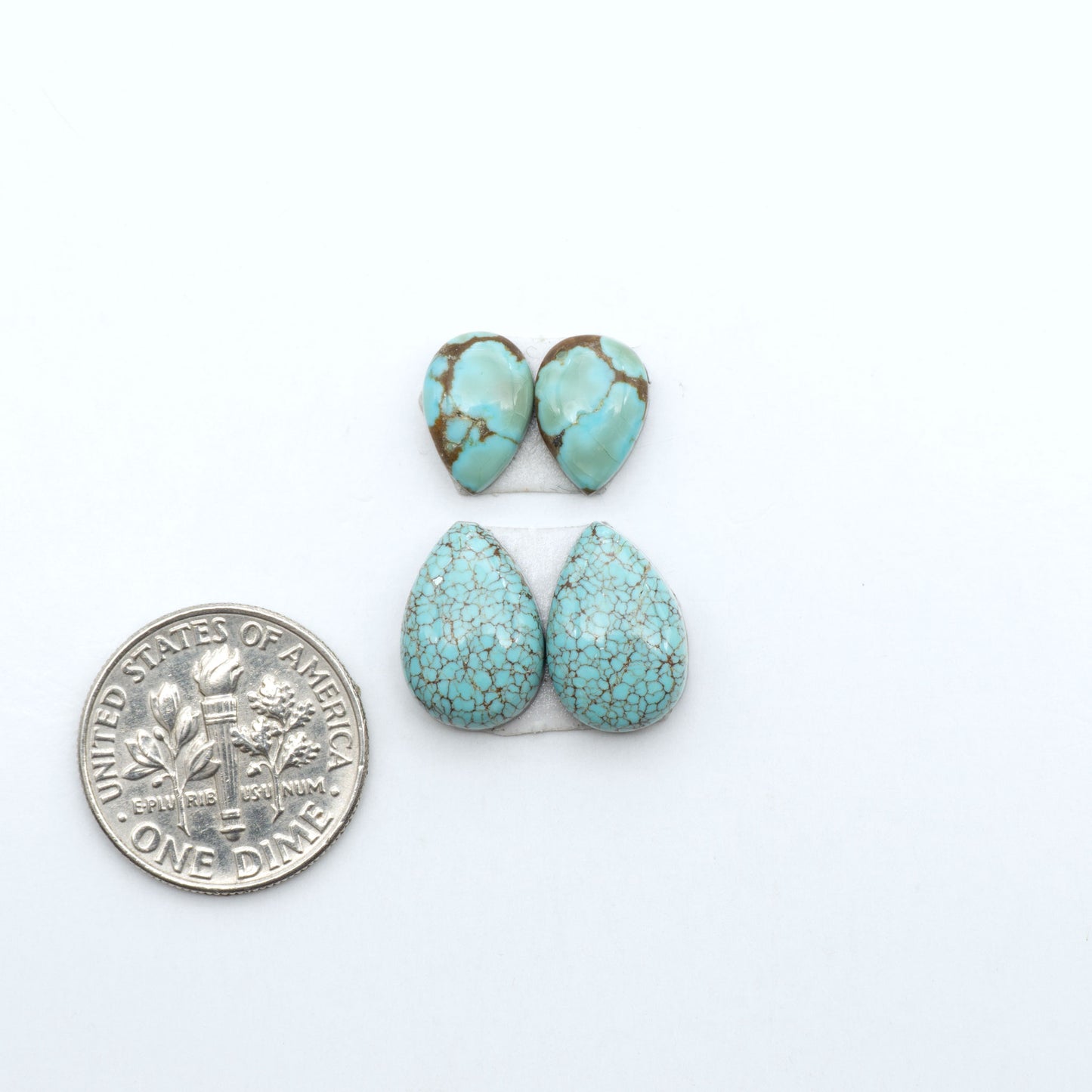 Number 8 Turquoise cabochons, blue and green color with brown matrix, polished stones on a white background, with a US dime for scale