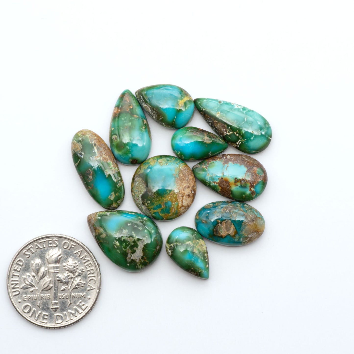 Sonoran Mountain Turquoise cabochons, blue-green color with natural matrix, polished stones on a white background, with a US dime for scale