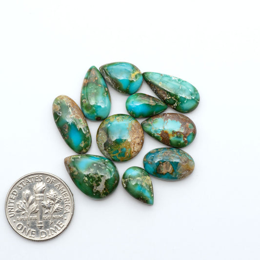 Sonoran Mountain Turquoise cabochons, blue-green color with natural matrix, polished stones on a white background, with a US dime for scale