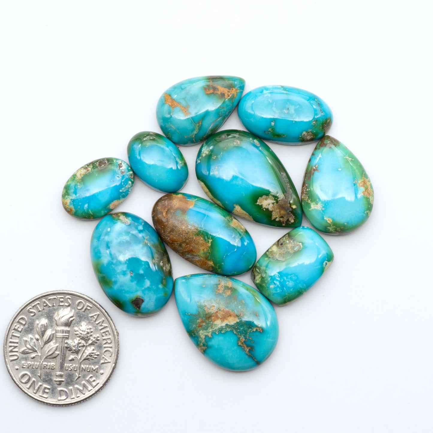 Sonoran Mountain Turquoise cabochons, blue-green color with natural matrix, polished stones on a white background, with a US dime for scale