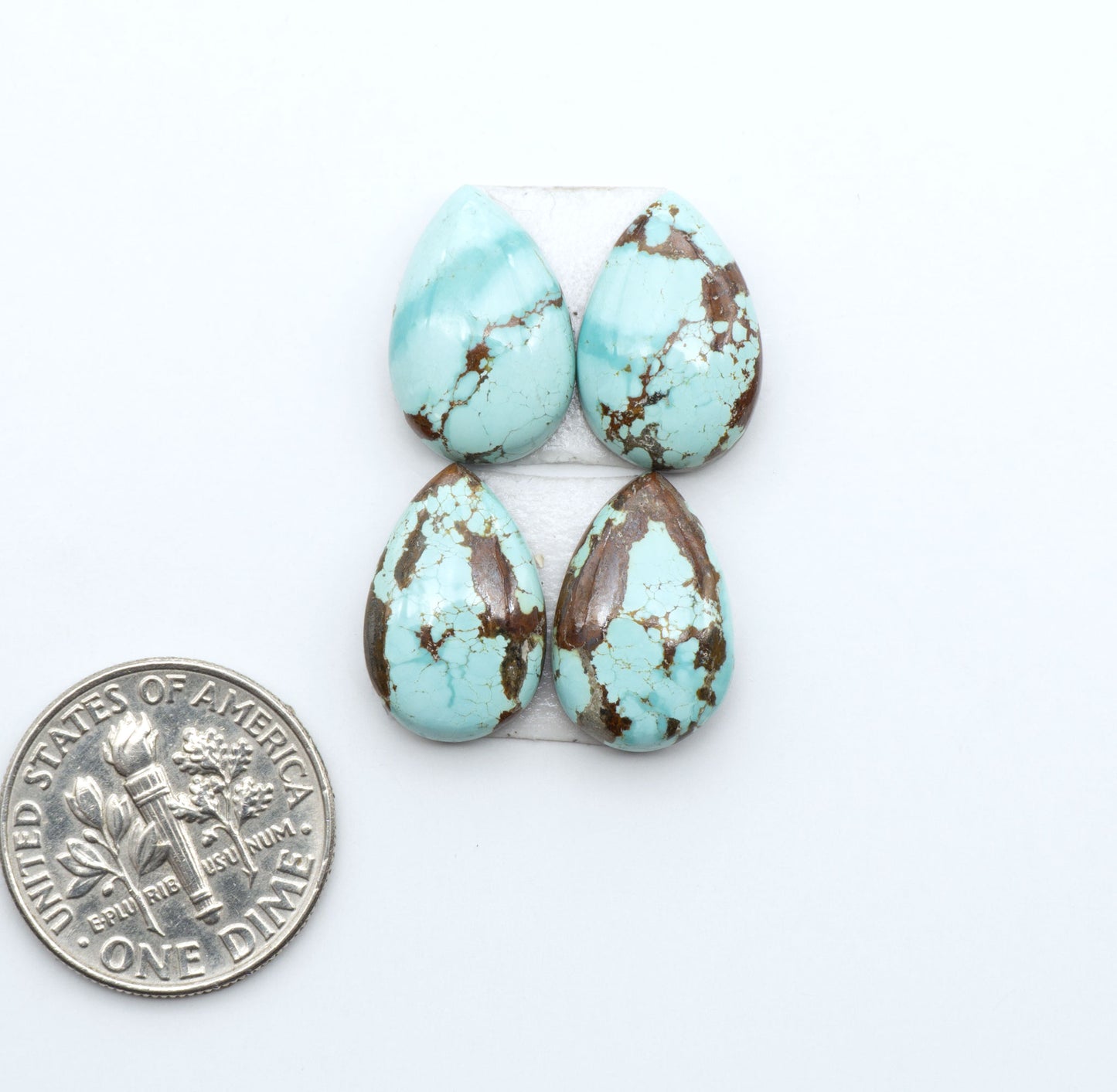 Number 8 Turquoise cabochons, blue and green color with brown matrix, polished stones on a white background, with a US dime for scale