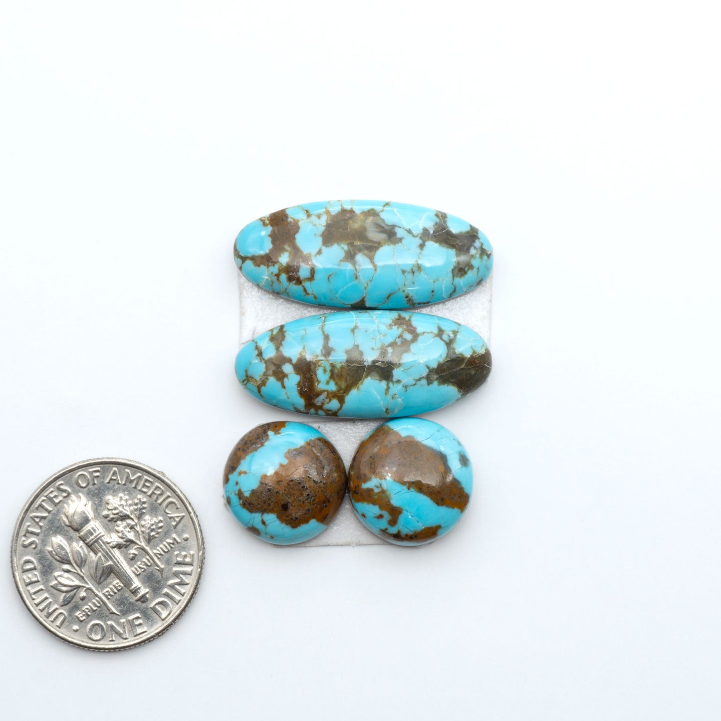 Number 8 Turquoise cabochons, blue and green color with brown matrix, polished stones on a white background, with a US dime for scale