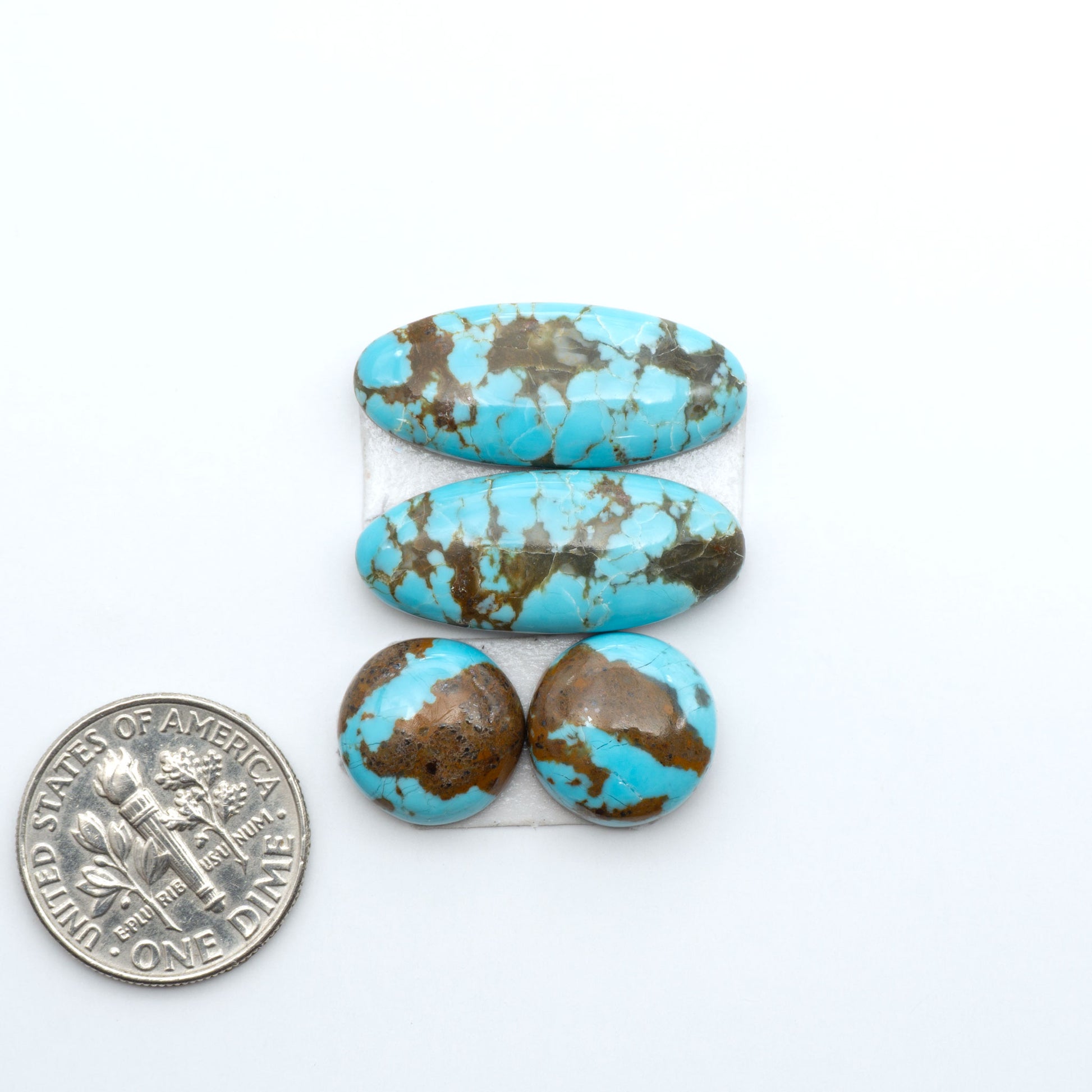 Number 8 Turquoise cabochons, blue and green color with brown matrix, polished stones on a white background, with a US dime for scale