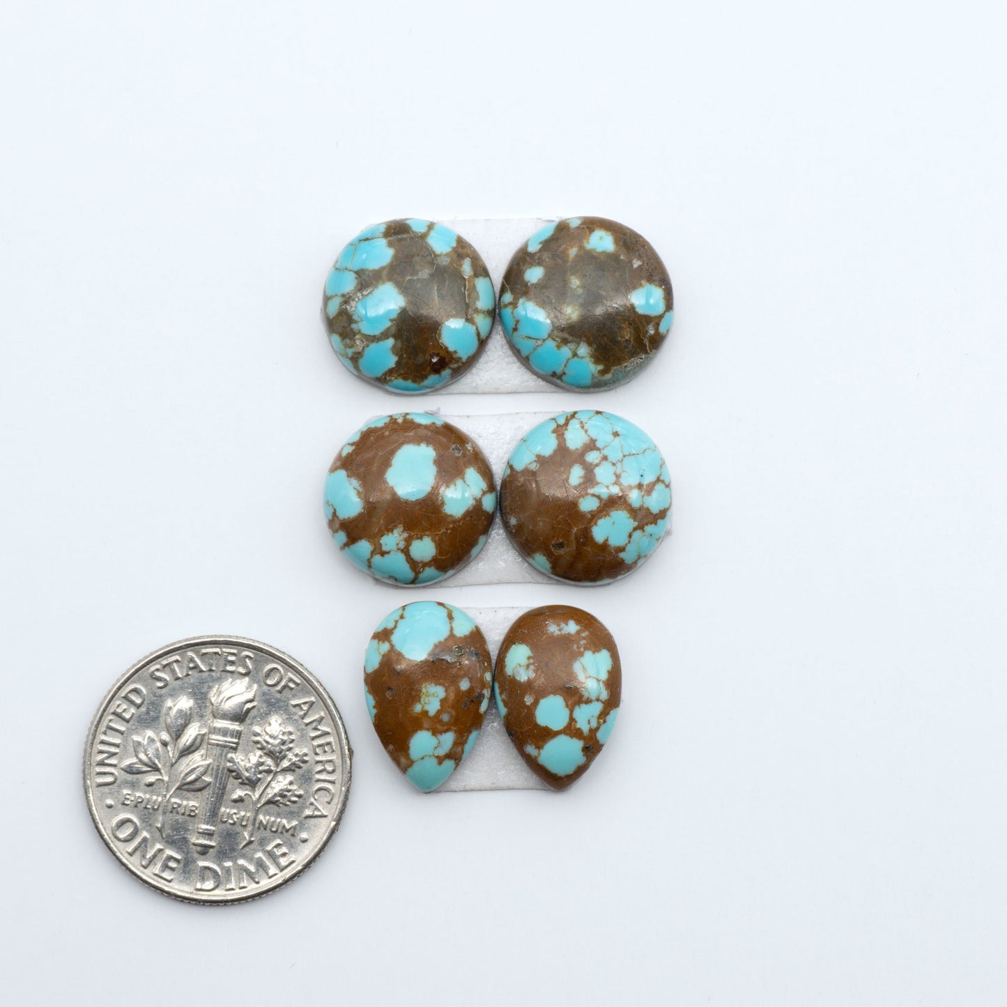 Number 8 Turquoise cabochons, blue and green color with brown matrix, polished stones on a white background, with a US dime for scale