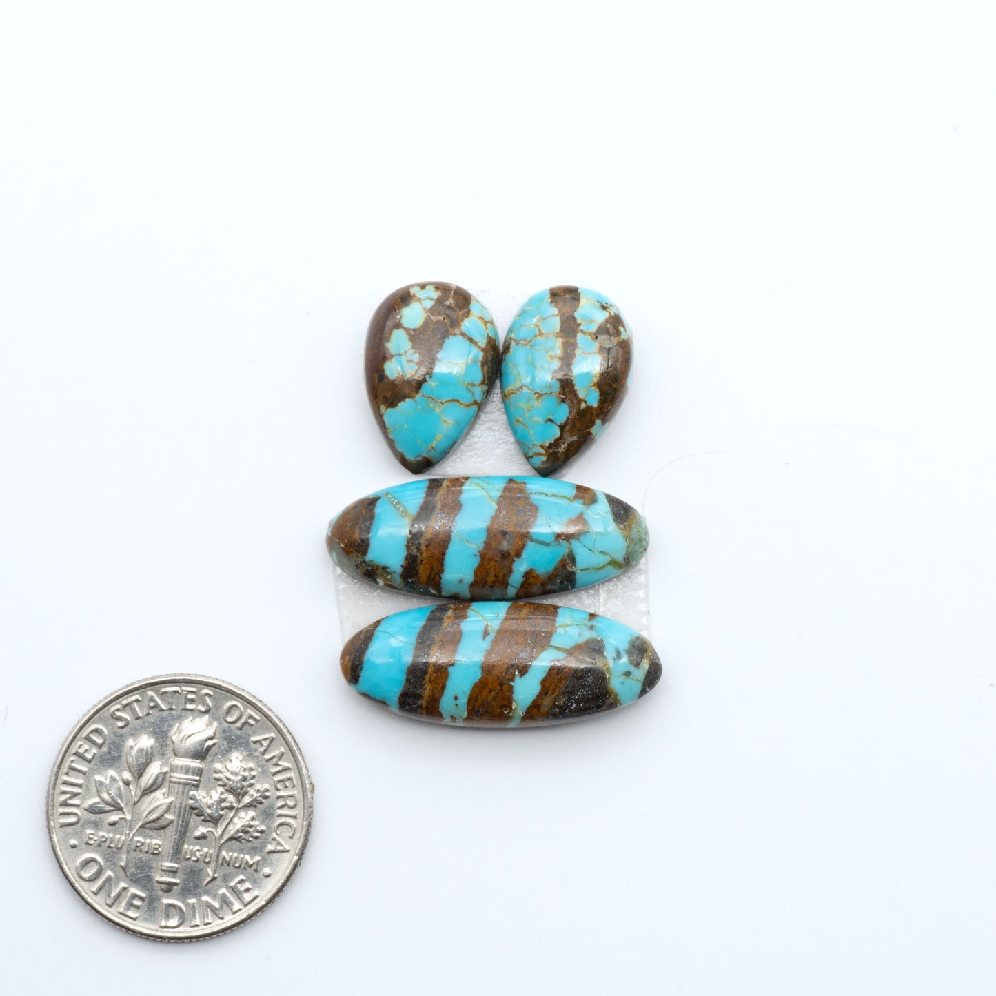 Number 8 Turquoise cabochons, blue and green color with brown matrix, polished stones on a white background, with a US dime for scale