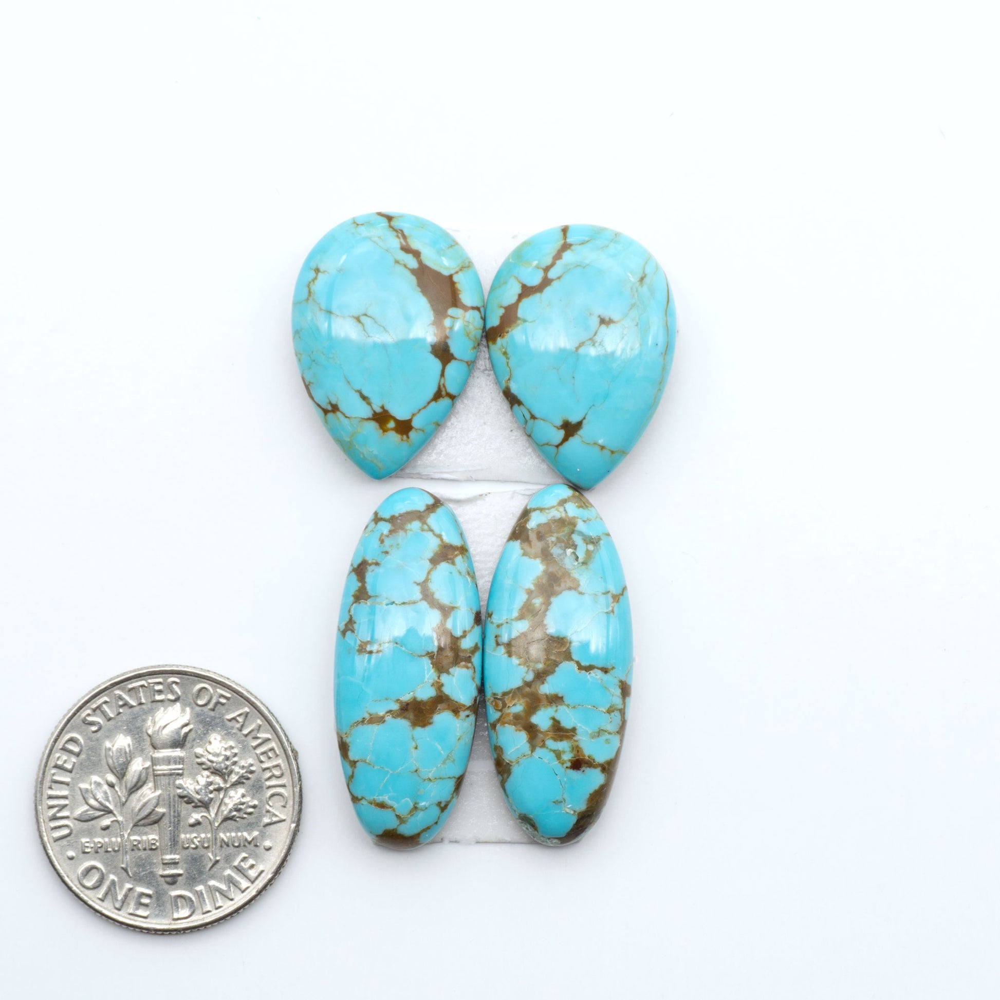 Number 8 Turquoise cabochons, blue and green color with brown matrix, polished stones on a white background, with a US dime for scale