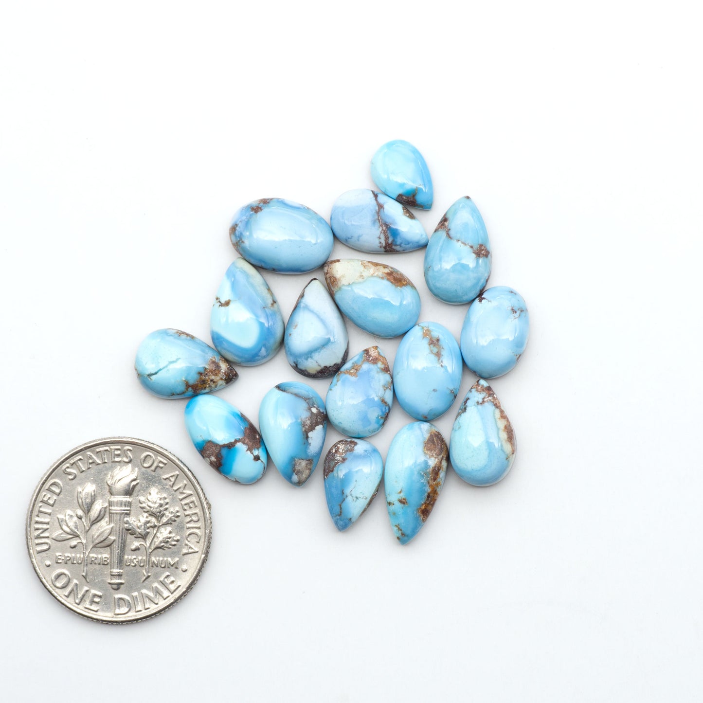 Golden Hills Turquoise cabochons, icy blue to lavender tones with chocolate matrix, polished stones on a white background with a US dime for scale