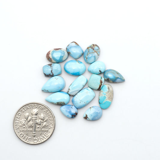 Golden Hills Turquoise cabochons, icy blue to lavender tones with chocolate matrix, polished stones on a white background with a US dime for scale
