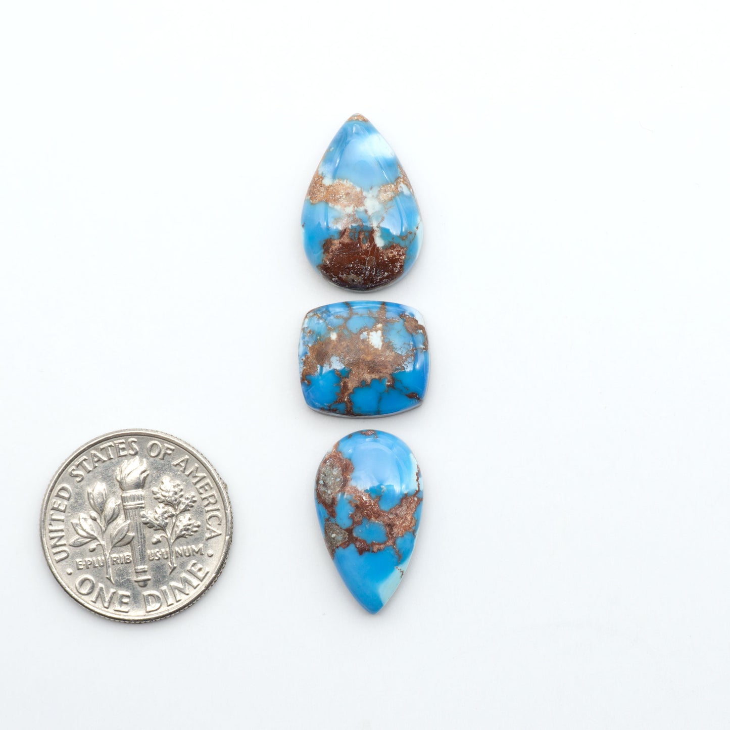 Golden Hills Turquoise cabochons, icy blue to lavender tones with chocolate matrix, polished stones on a white background with a US dime for scale
