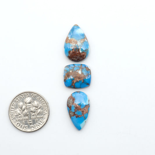 Golden Hills Turquoise cabochons, icy blue to lavender tones with chocolate matrix, polished stones on a white background with a US dime for scale