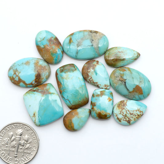 Pilot Mountain Turquoise cabochons, blue-green gemstones with natural matrix on a white background with a US dime for scale