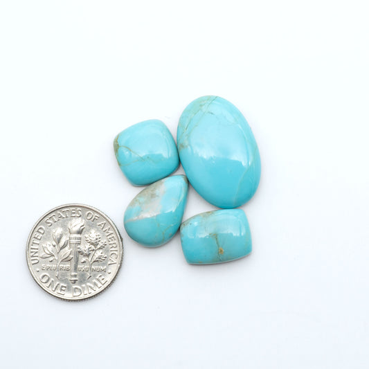Pilot Mountain Turquoise cabochons, blue-green gemstones with natural matrix on a white background with a US dime for scale