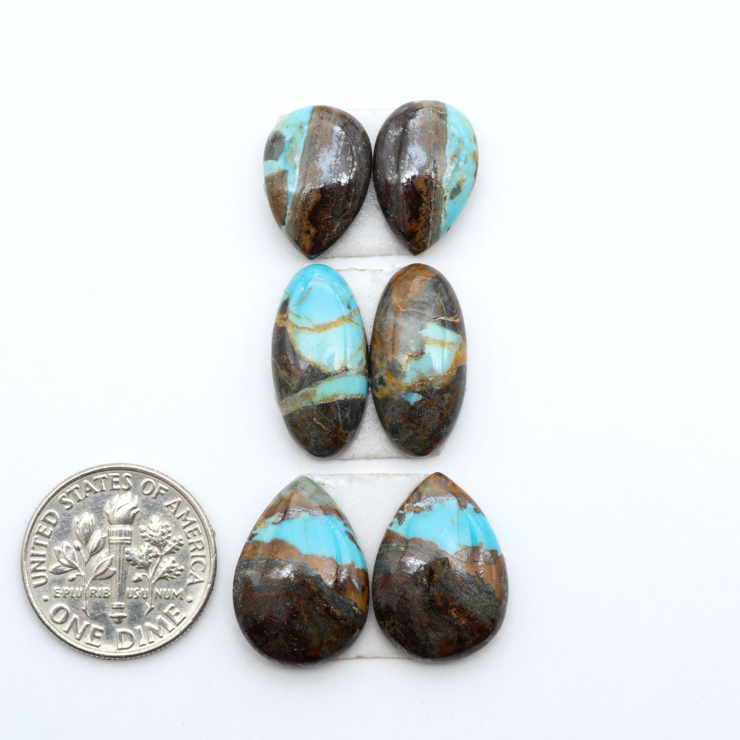 Number 8 Turquoise cabochons, blue and green color with brown matrix, polished stones on a white background, with a US dime for scale