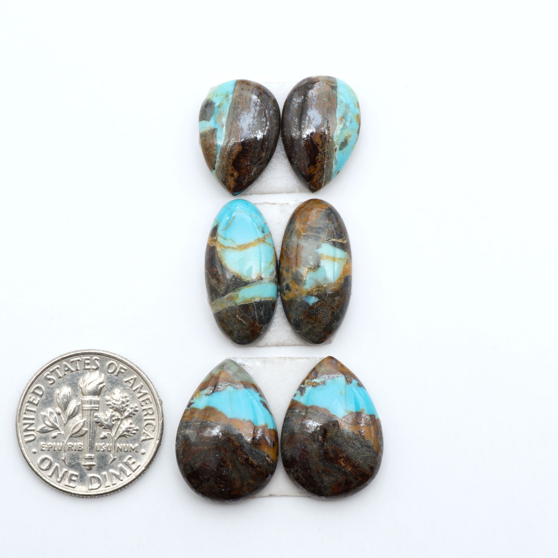 Number 8 Turquoise cabochons, blue and green color with brown matrix, polished stones on a white background, with a US dime for scale
