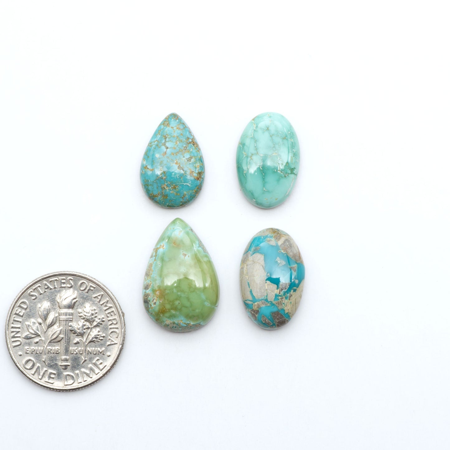 Fox Turquoise cabochons, polished gemstones with natural matrix on a white background, with a US dime for scale