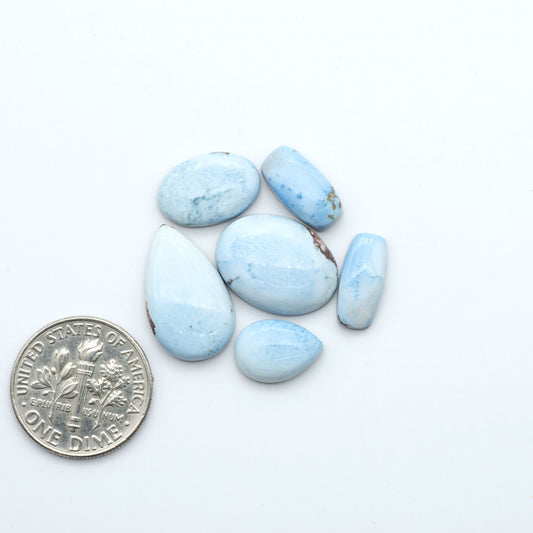 Golden Hills Turquoise cabochons, icy blue to lavender tones with chocolate matrix, polished stones on a white background with a US dime for scale