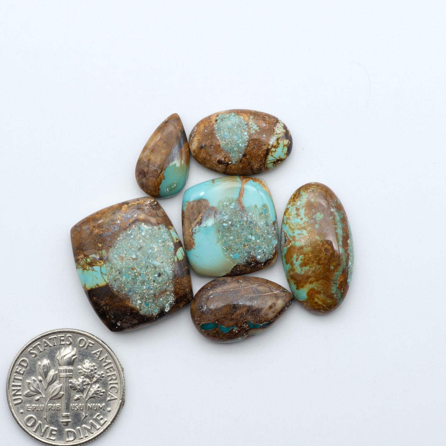 Royston Turquoise cabochons, blue-green color with natural matrix, polished stones on a white background, with a US dime for scale