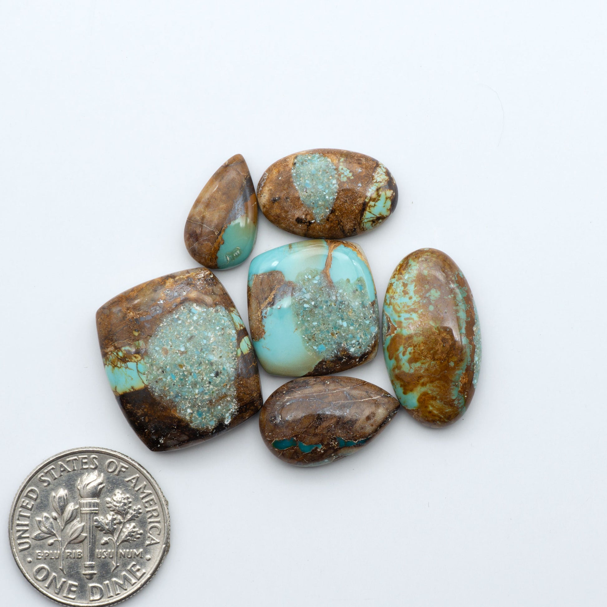 Royston Turquoise cabochons, blue-green color with natural matrix, polished stones on a white background, with a US dime for scale