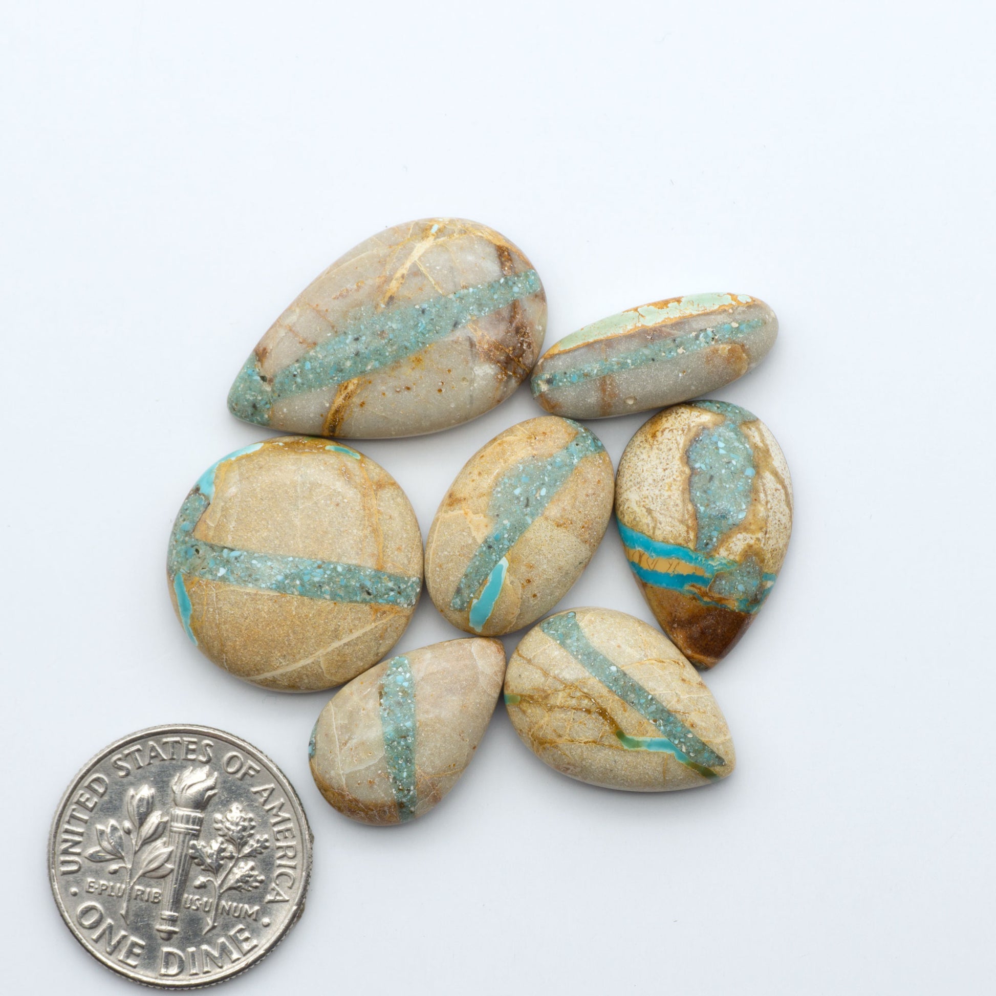 Royston Turquoise cabochons, blue-green color with natural matrix, polished stones on a white background, with a US dime for scale