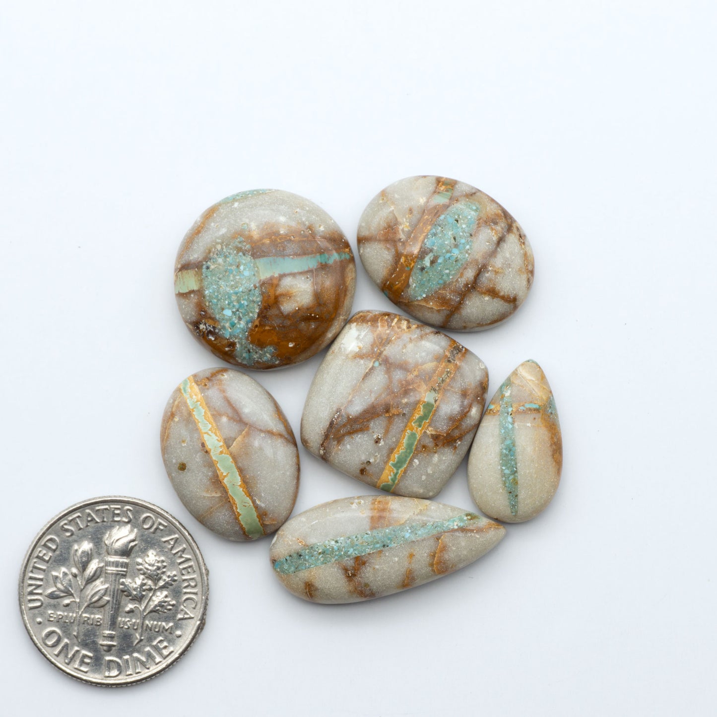 Royston Turquoise cabochons, blue-green color with natural matrix, polished stones on a white background, with a US dime for scale