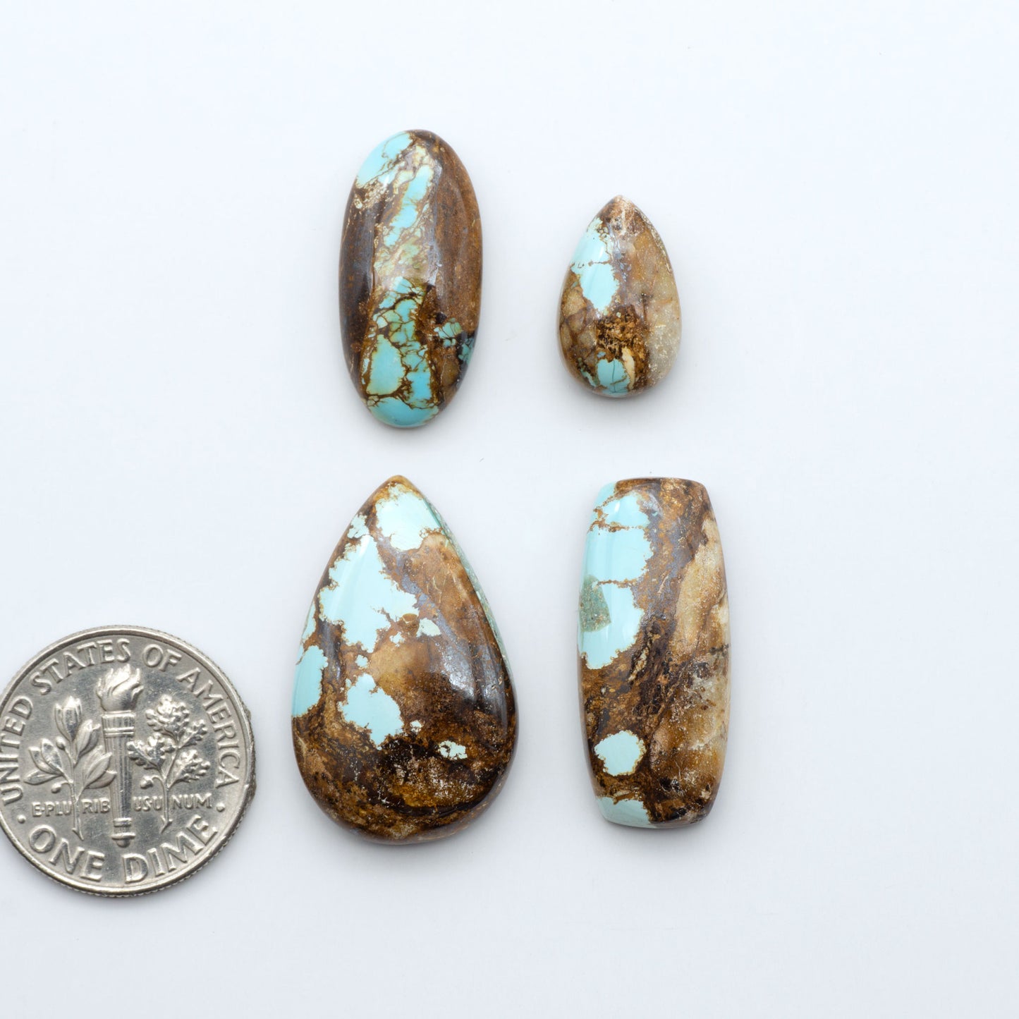Royston Turquoise cabochons, blue-green color with natural matrix, polished stones on a white background, with a US dime for scale