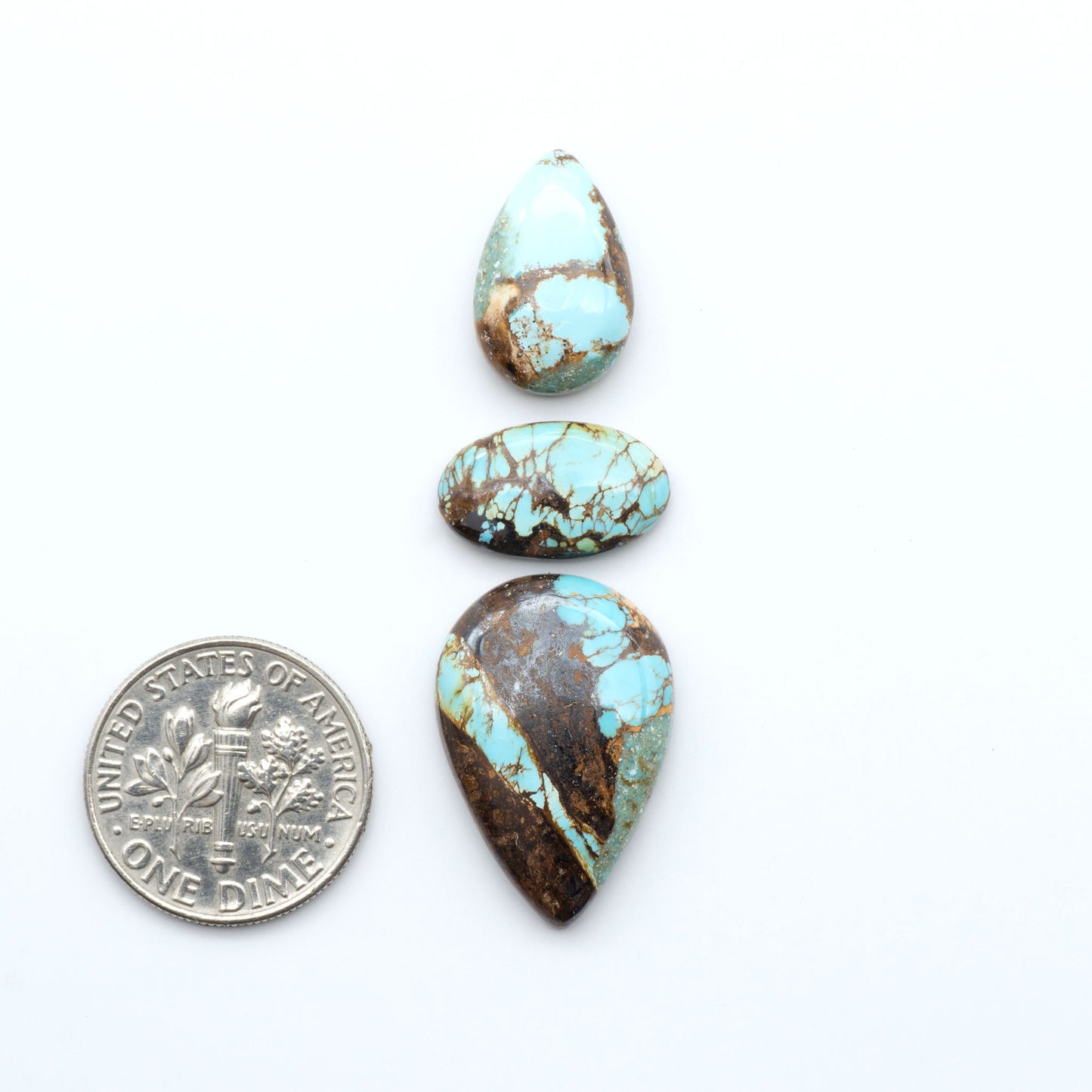 Royston Turquoise cabochons, blue-green color with natural matrix, polished stones on a white background, with a US dime for scale