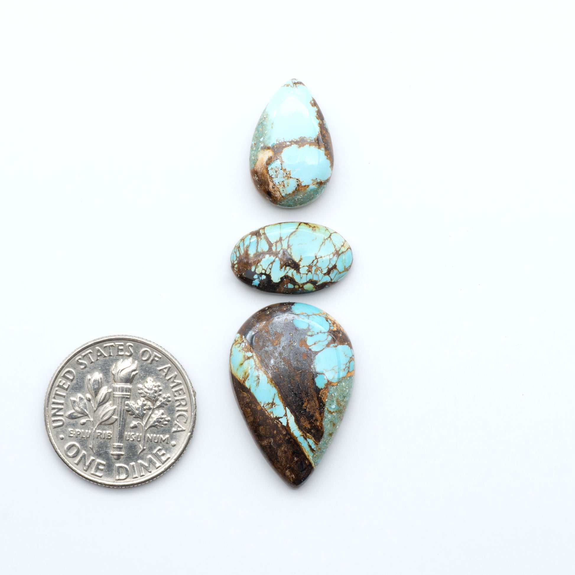 Royston Turquoise cabochons, blue-green color with natural matrix, polished stones on a white background, with a US dime for scale