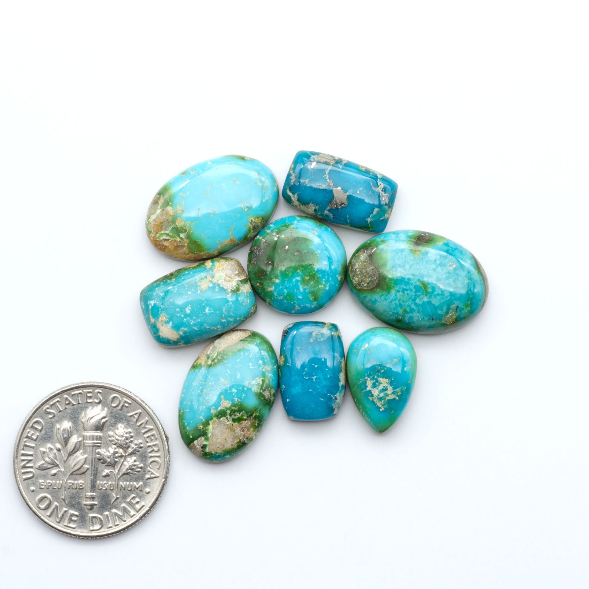 Sonoran Mountain Turquoise cabochons, blue-green color with natural matrix, polished stones on a white background, with a US dime for scale