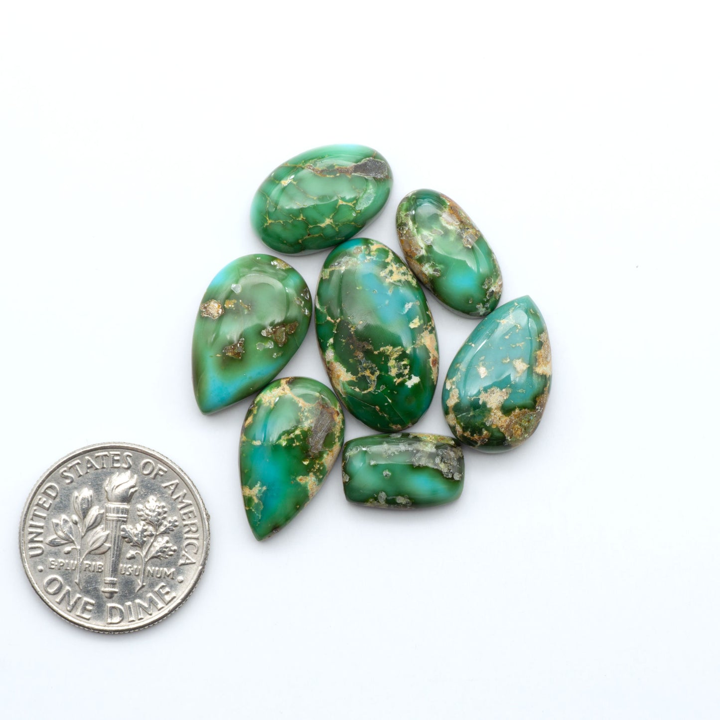 Sonoran Mountain Turquoise cabochons, blue-green color with natural matrix, polished stones on a white background, with a US dime for scale