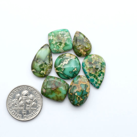 Sonoran Mountain Turquoise cabochons, blue-green color with natural matrix, polished stones on a white background, with a US dime for scale