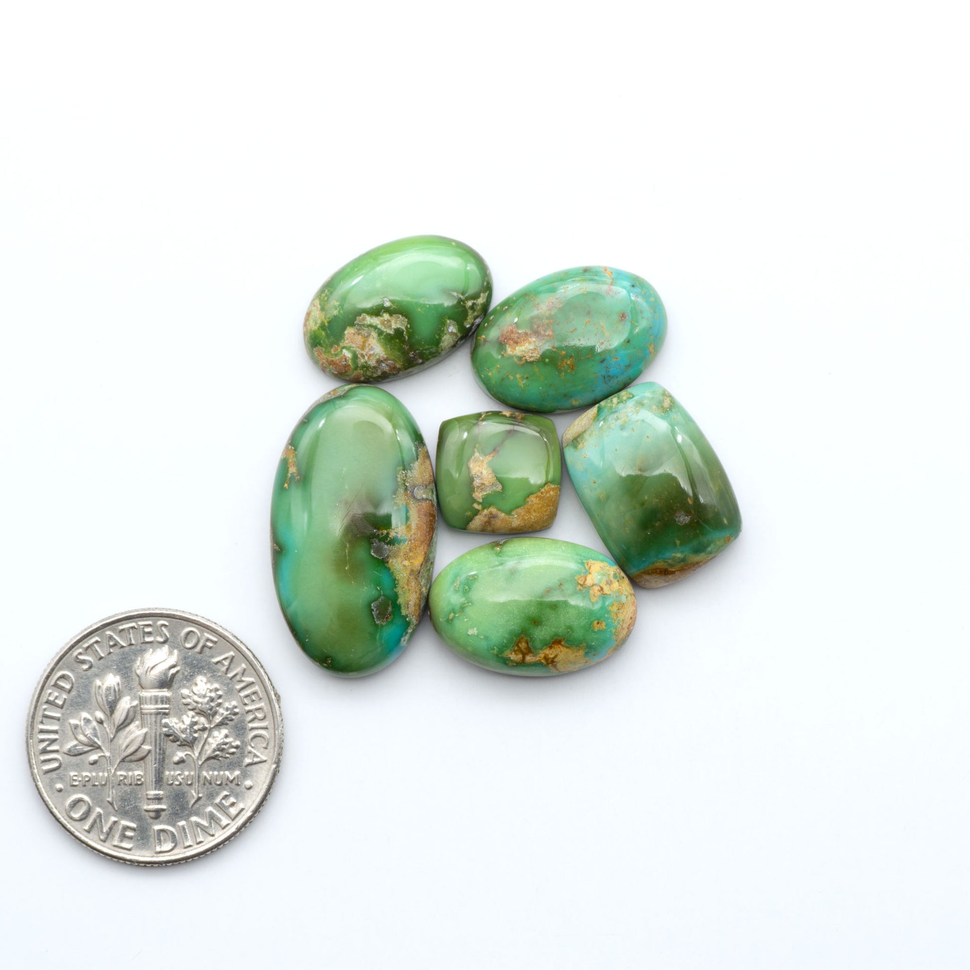 Sonoran Mountain Turquoise cabochons, blue-green color with natural matrix, polished stones on a white background, with a US dime for scale