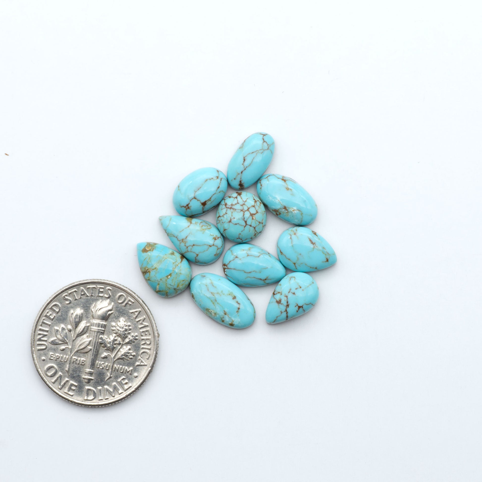 Number 8 Turquoise cabochons, blue and green color with brown matrix, polished stones on a white background, with a US dime for scale