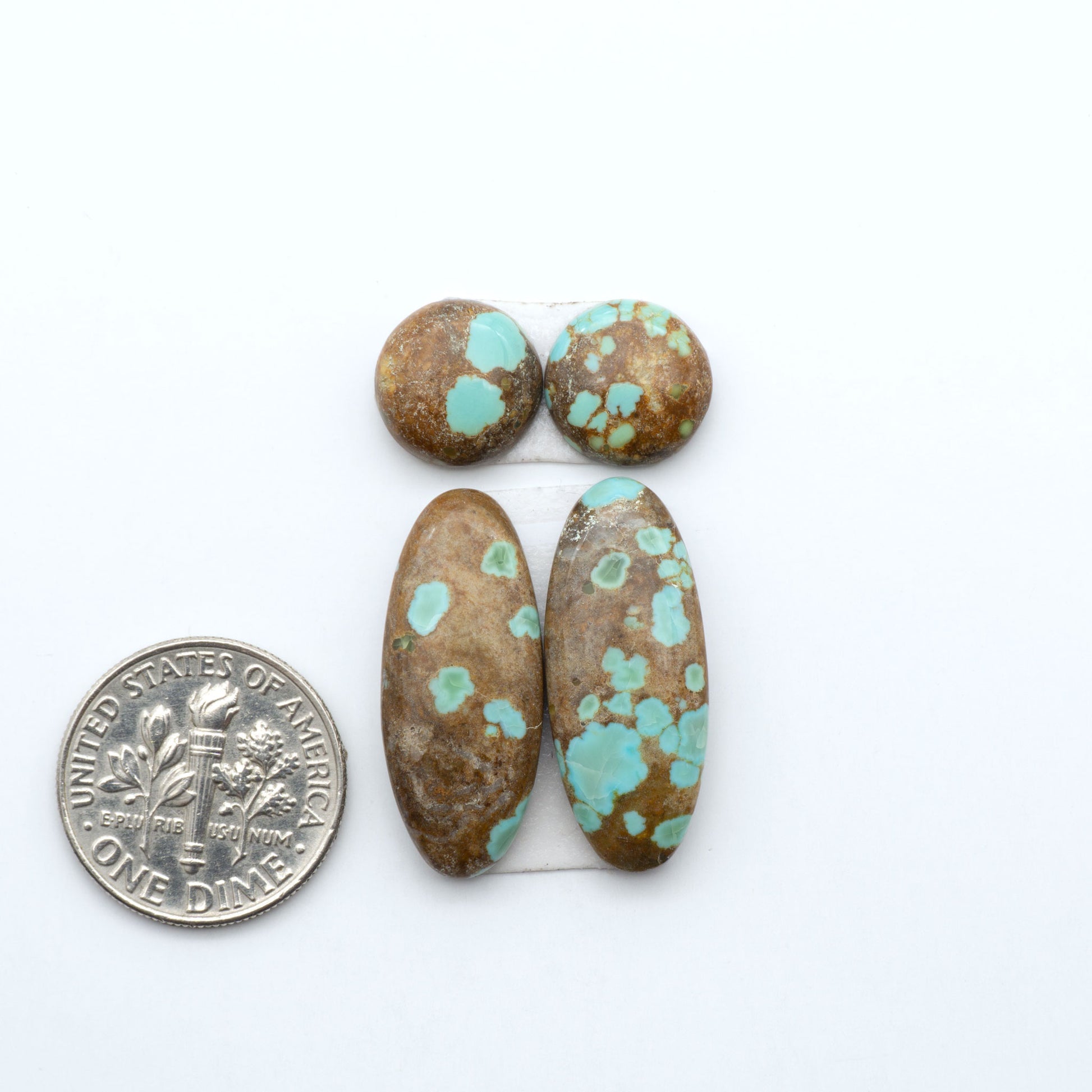 Number 8 Turquoise cabochons, blue and green color with brown matrix, polished stones on a white background, with a US dime for scale