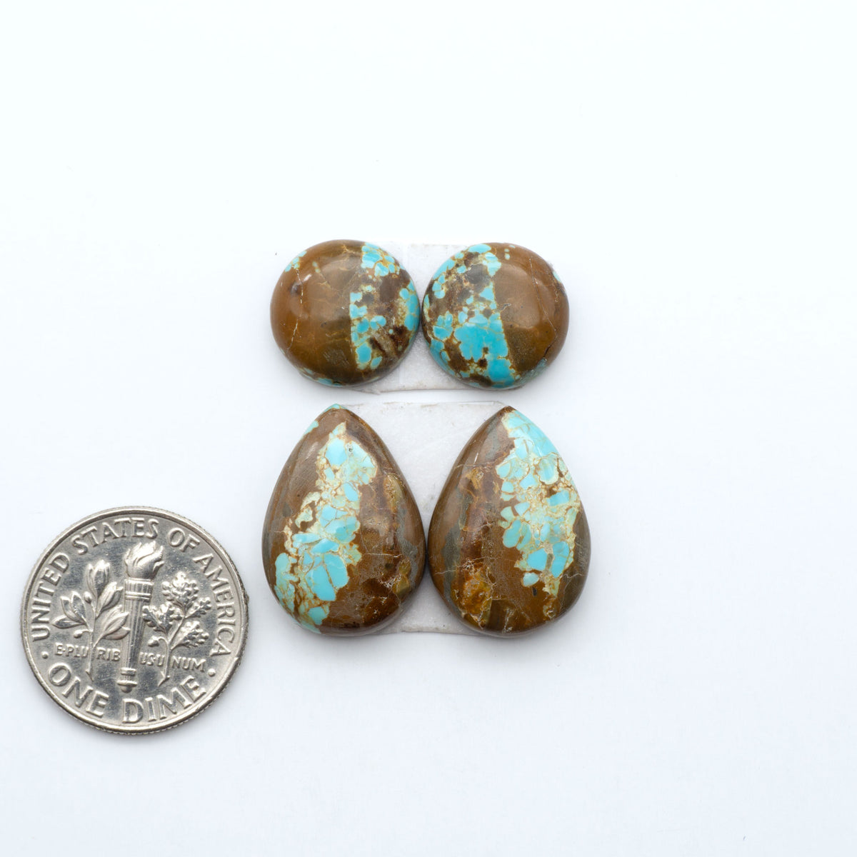 Number 8 Turquoise cabochons, blue and green color with brown matrix, polished stones on a white background, with a US dime for scale