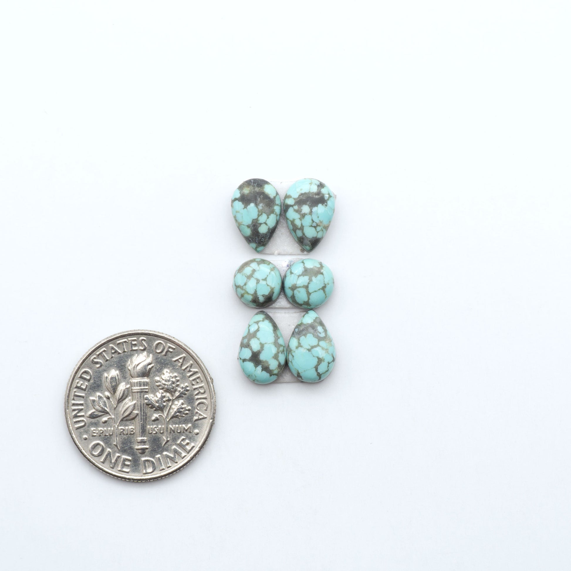 Number 8 Turquoise cabochons, blue and green color with brown matrix, polished stones on a white background, with a US dime for scale