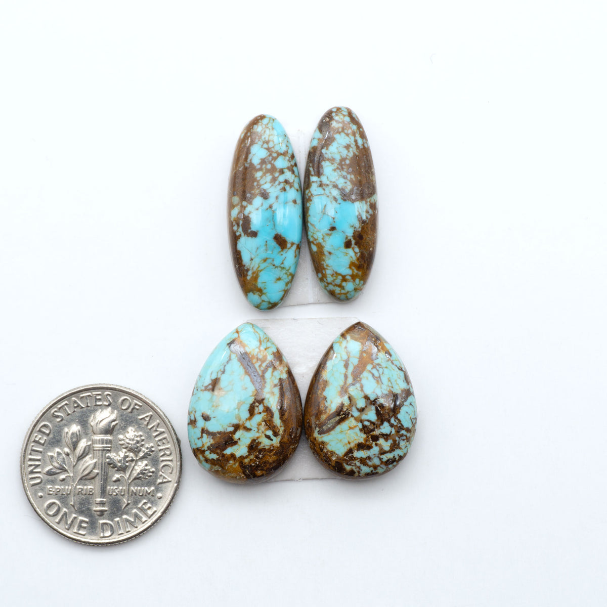 Number 8 Turquoise cabochons, blue and green color with brown matrix, polished stones on a white background, with a US dime for scale