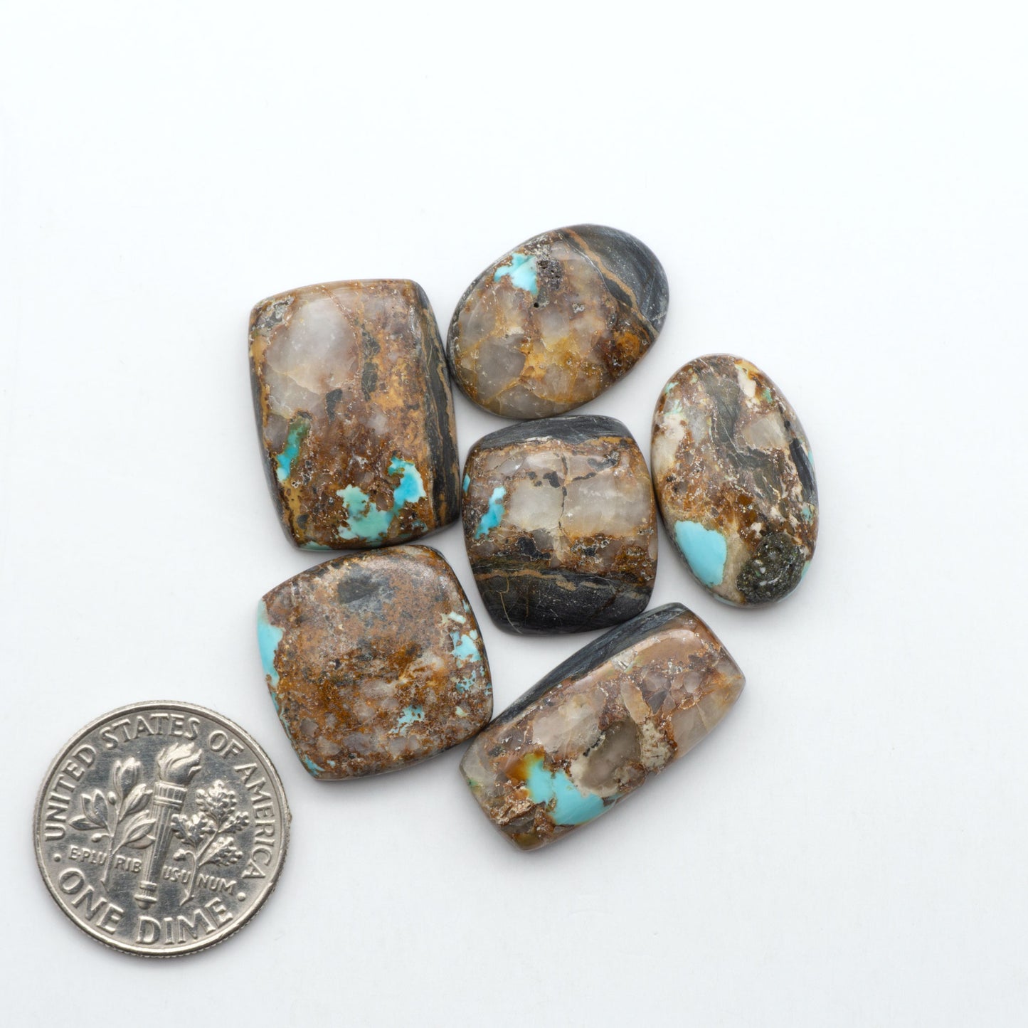 Black Jack turquoise cabochons, blue-green color with black matrix, polished stones on a white background with a US dime for scale