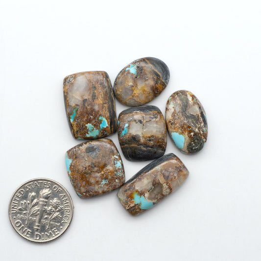 Black Jack turquoise cabochons, blue-green color with black matrix, polished stones on a white background with a US dime for scale