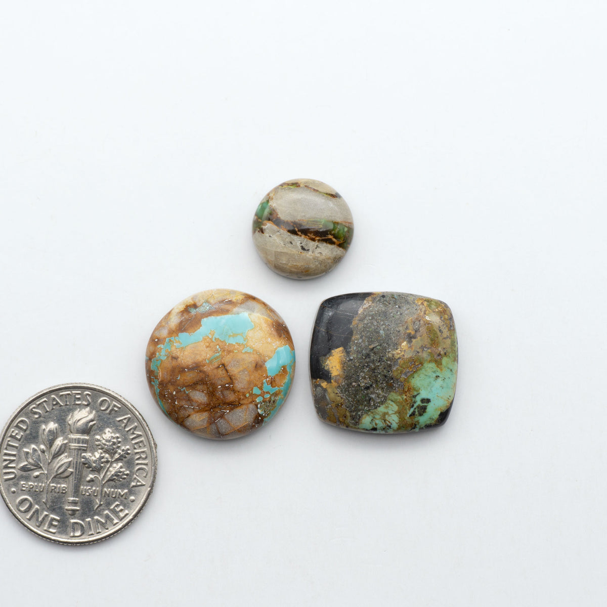 Black Jack turquoise cabochons, blue-green color with black matrix, polished stones on a white background with a US dime for scale