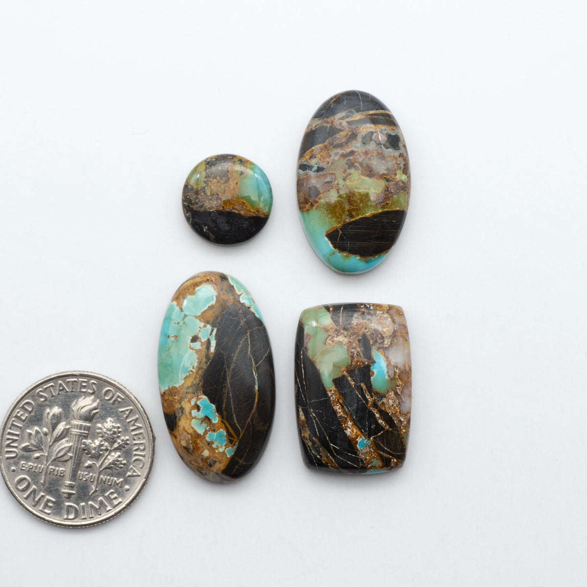 Black Jack turquoise cabochons, blue-green color with black matrix, polished stones on a white background with a US dime for scale